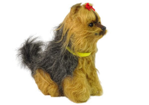 Plüschhund mit roter Schleife und gelbem Halsband, seitlich fotografiert.