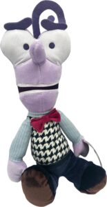 Eine bunte Stoffpuppe mit lilafarbenem Kopf, kariertem Hemd und roter Fliege.