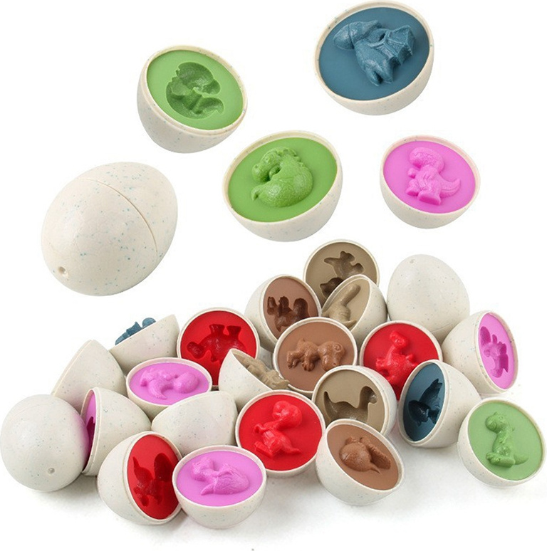 Bunte geöffnete Spielzeug-Eier mit Dinosaurierformen innen auf weißem Hintergrund. Bunte geöffnete Spielzeug-Eier mit Dinosaurierformen innen auf weißem Hintergrund.