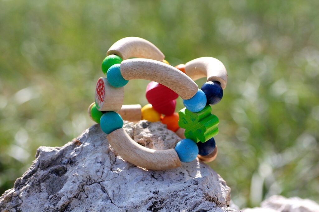 Buntes Holzspielzeug mit Perlen auf einem Felsen im Freien.
